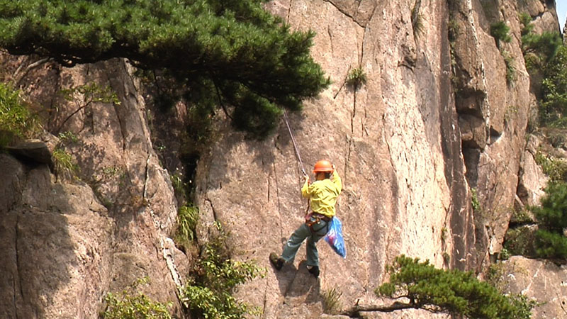 李培生在悬崖上捡拾垃圾。 余建辉 摄