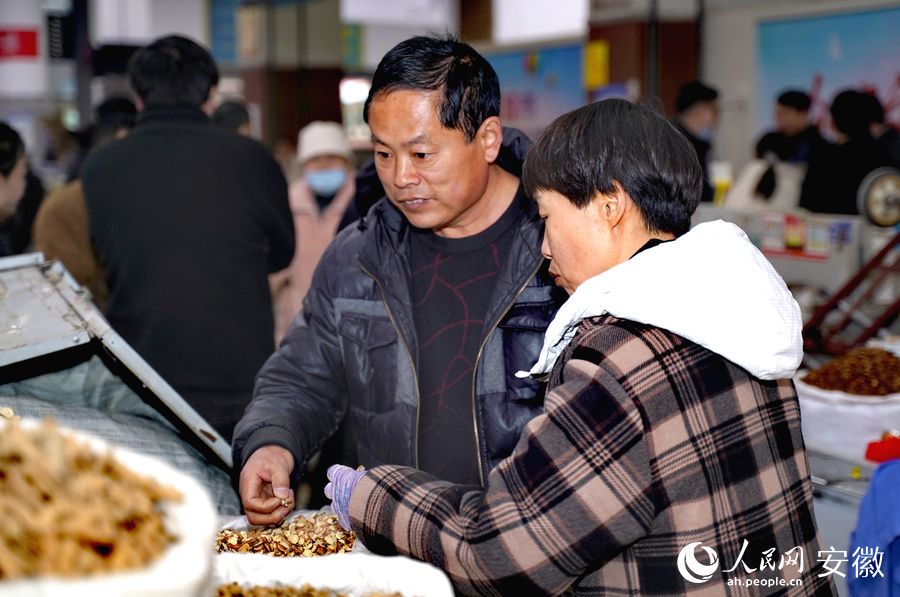 顾客正在中药材市场里的摊位前挑选中药材。人民网 王锐摄