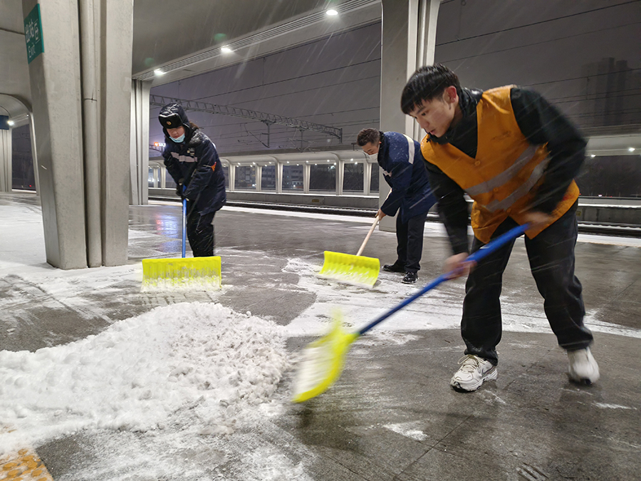 工作人员深夜清扫站台积雪，为雪夜旅客出行铺设安全通道。宿州火车站供图